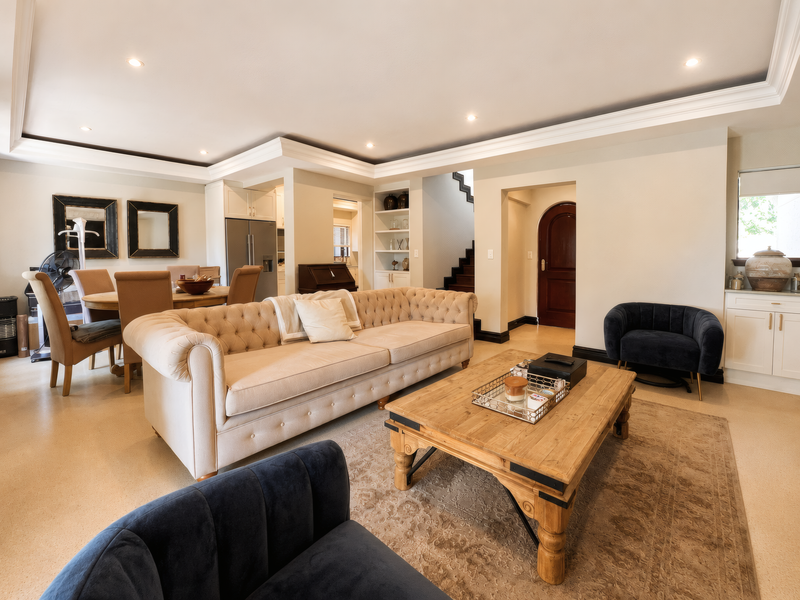 Spacious open-plan living and dining area featuring recessed ceiling lighting, built-in shelving, and an elegant arched doorway leading to the staircase.