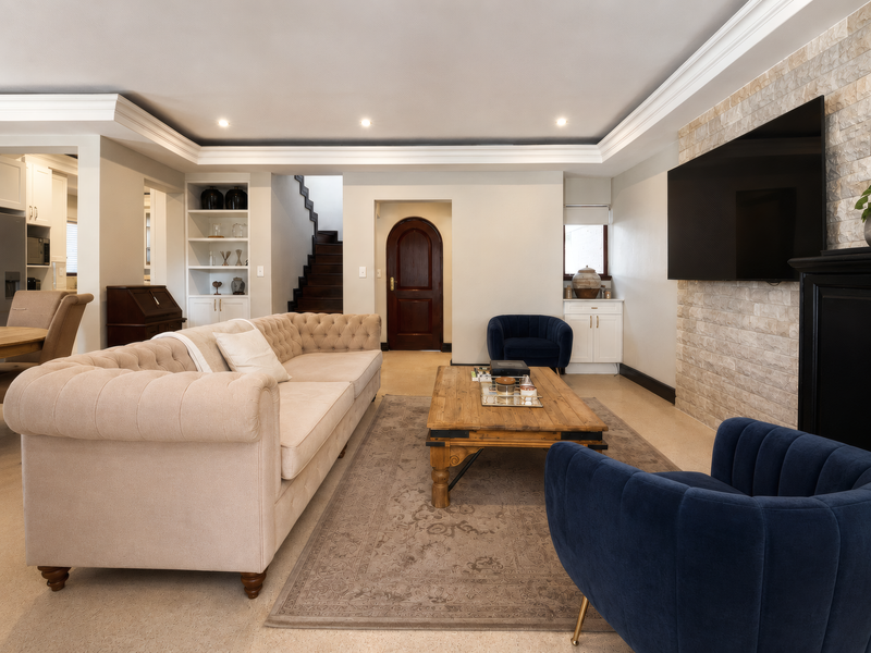 Spacious living room featuring a stone accent wall, built-in shelving, crown molding, and elegant architectural details including an arched doorway and staircase.