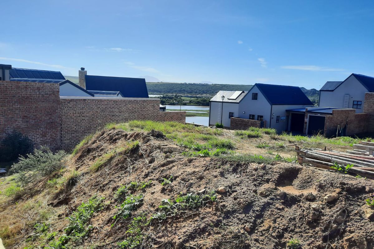 A view from the vacant residential plot overlooking neighbouring properties and a scenic water body in the distance.