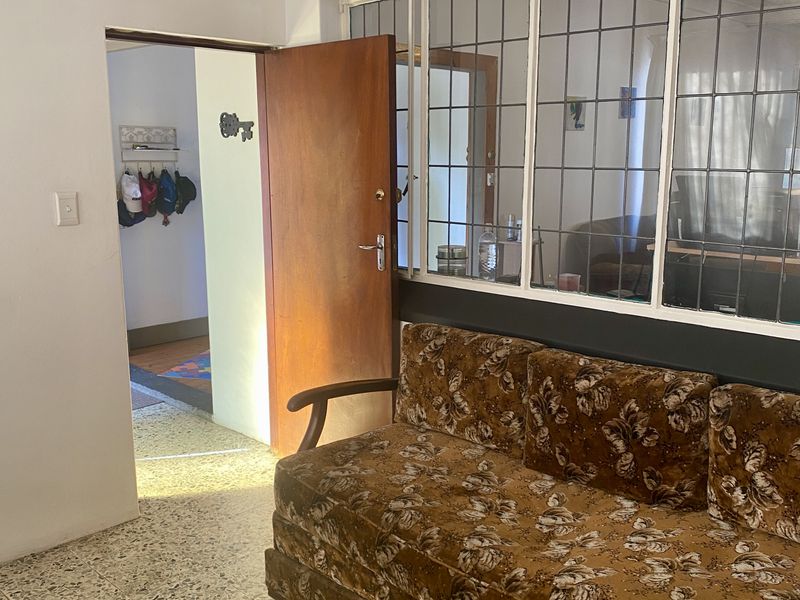 Living area featuring classic terrazzo flooring, a leaded glass window partition, and a timber door leading to an adjacent hallway.