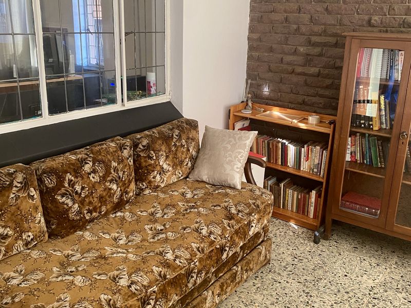 Living room featuring classic terrazzo flooring, an exposed brick feature wall, and a large leaded glass window providing natural light.