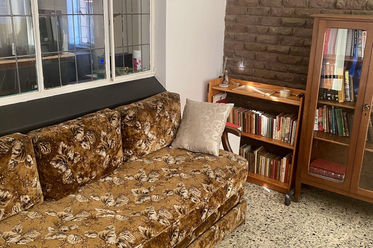 Living room featuring classic terrazzo flooring, an exposed brick feature wall, and a large leaded glass window providing natural light.