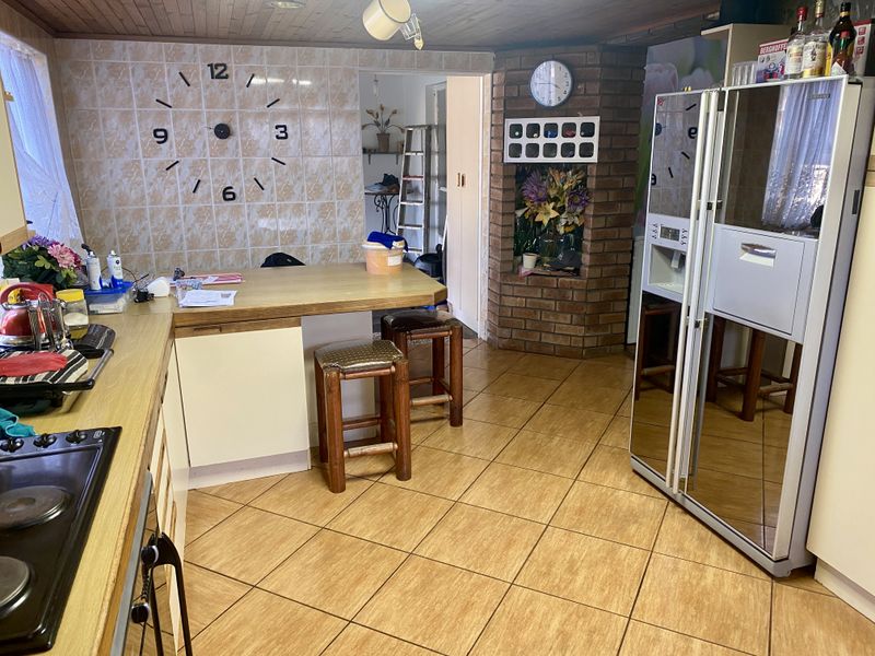 A functional kitchen featuring a brick accent wall, timber ceiling, and tiled flooring, offering a dated aesthetic with potential for modern renovation.