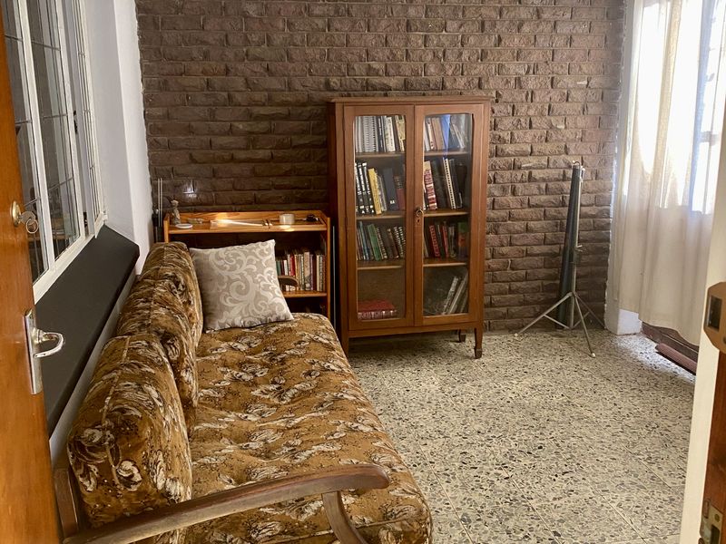 A living area featuring a textured exposed brick wall, durable terrazzo flooring, and a classic leaded glass window.