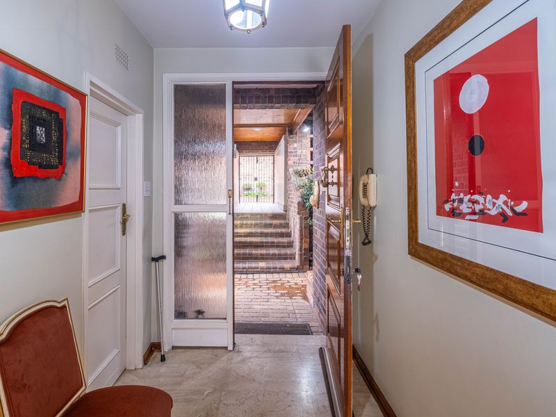 Welcoming entrance hall featuring stone flooring, a solid wood front door with a textured glass sidelight, and an integrated intercom system.