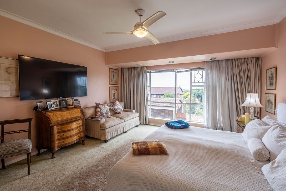 Spacious bedroom featuring a ceiling fan, recessed lighting, and large windows providing natural light and exterior views.
