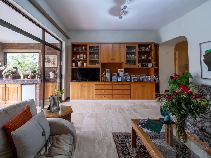 Spacious living room featuring elegant travertine flooring, extensive built-in wooden cabinetry, and large sliding glass doors providing seamless access to the patio area.