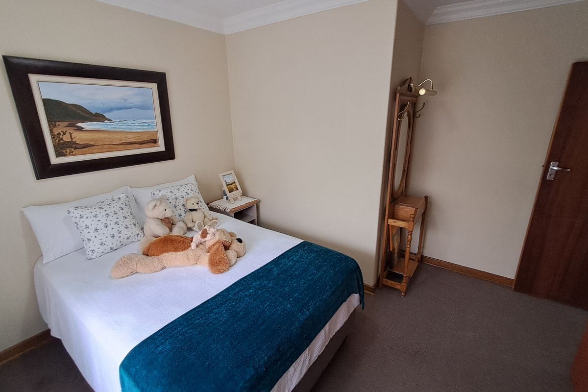 A cozy bedroom featuring neutral wall tones, carpeted flooring, and classic cove cornice detailing.