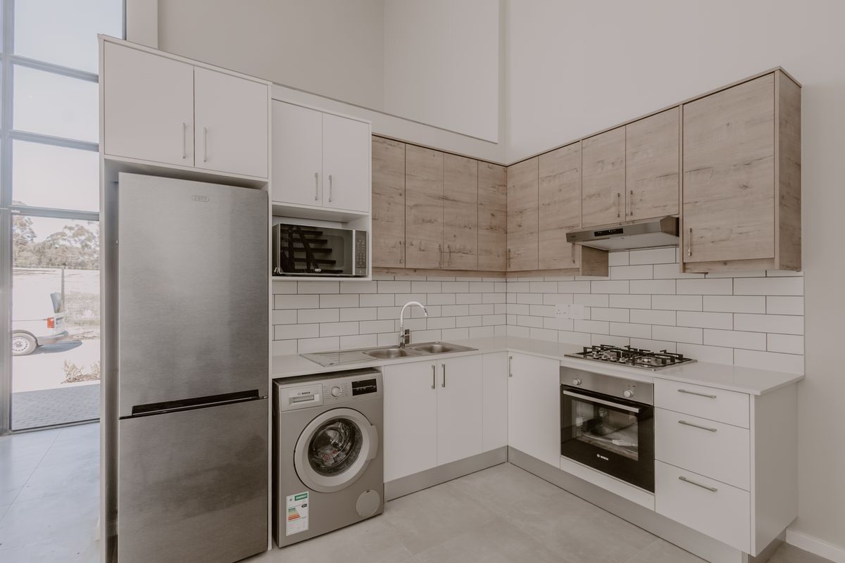 Modern kitchen featuring two-tone cabinetry, subway tile backsplash, integrated appliances, gas hob, and a large floor-to-ceiling window providing ample natural light.