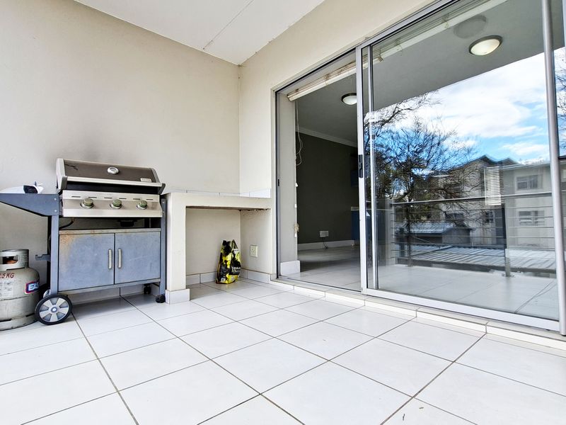 A covered balcony featuring tiled flooring, a built-in masonry counter, and sliding glass doors providing access to the interior living space.