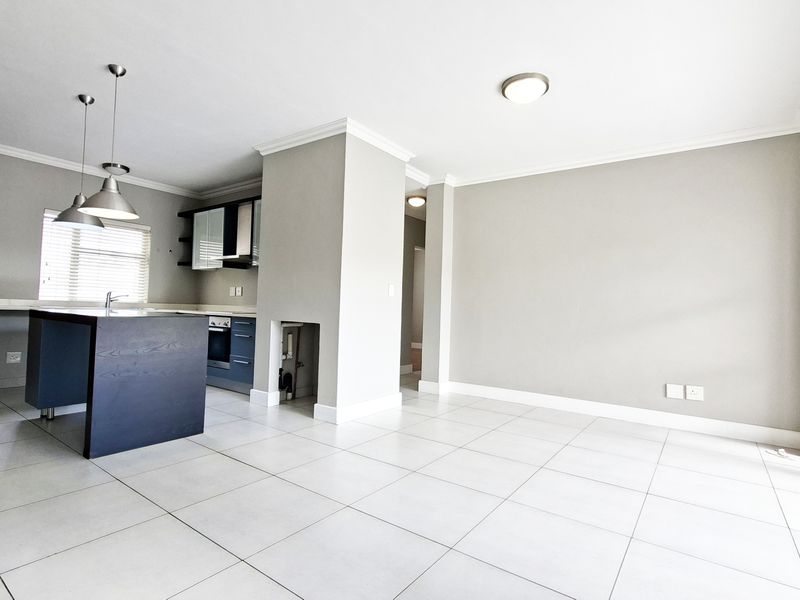 Spacious open-plan living and kitchen area featuring modern tiled flooring, a central kitchen island, and large sliding doors providing ample natural light.