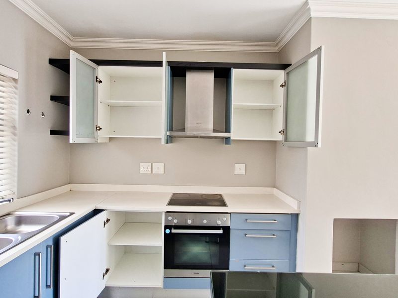 A functional kitchen featuring built-in cabinetry, a stainless steel sink, an electric hob, and an integrated oven with an extractor fan.
