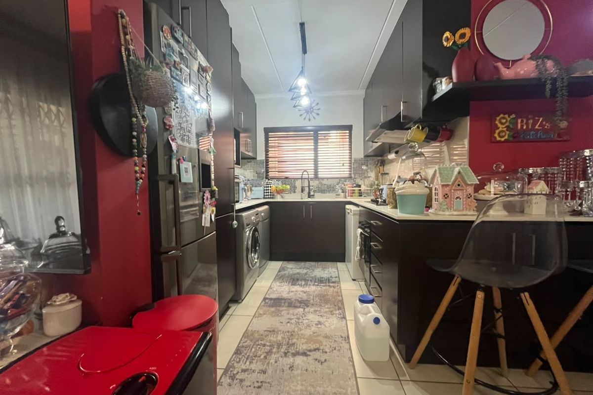 A compact kitchen featuring dark cabinetry, tiled flooring, and integrated appliances, offering a functional layout with a modern aesthetic.