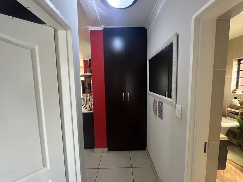 A functional hallway featuring tiled flooring and a tall, dark wood-finish built-in cupboard, providing convenient storage space within the apartment.