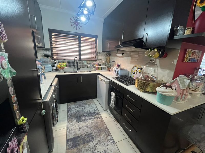 Compact kitchen featuring dark cabinetry, stone countertops, integrated gas hob, built-in oven, and tiled backsplash with a functional layout.