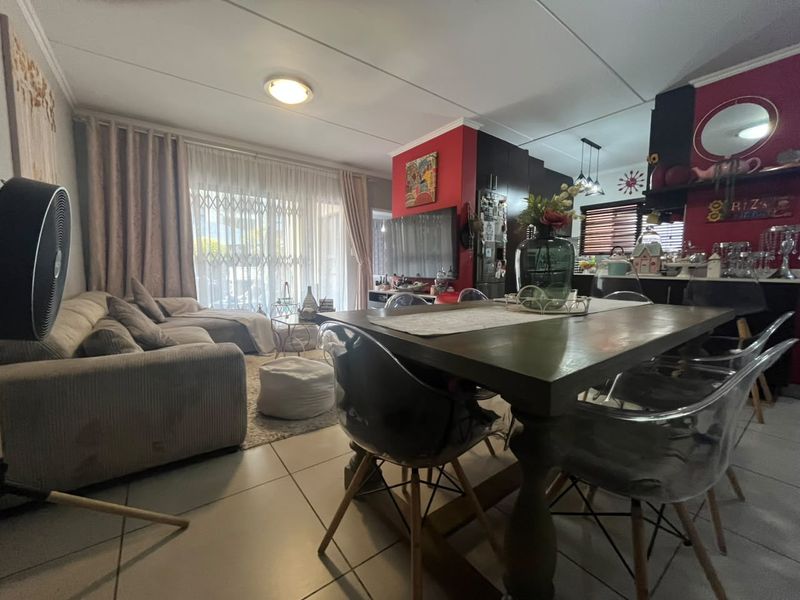 Open-plan living and dining area featuring tiled flooring, a security gate leading to the exterior, and an integrated kitchen space.