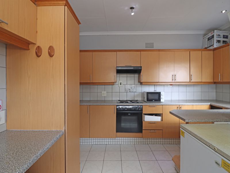 Functional kitchen featuring light wood-tone cabinetry, granite-look laminate countertops, built-in oven, gas hob, and tiled flooring.