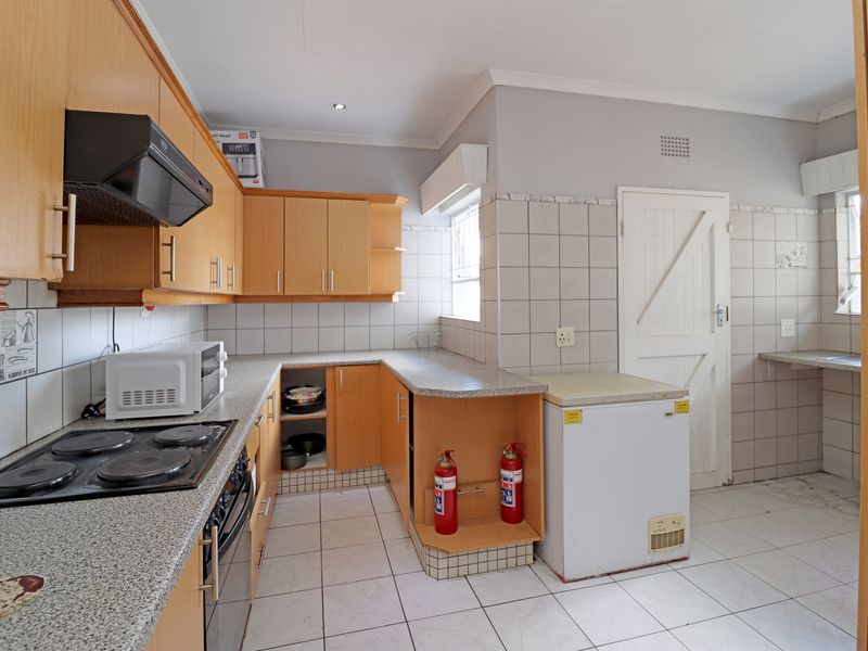 Functional kitchen featuring laminate cabinetry, granite-look countertops, ceramic tiling, and built-in cooking appliances, offering a practical layout for daily meal preparation.