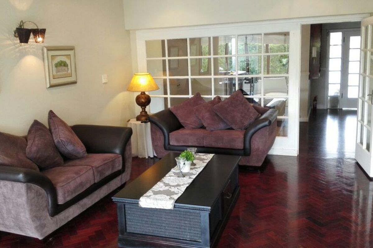 A cozy living room featuring rich herringbone parquet flooring and classic French doors leading to an adjacent space.