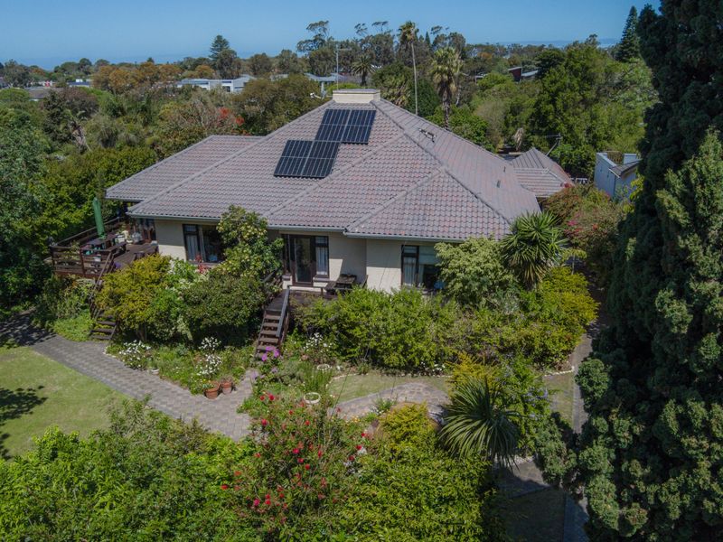 Aerial view of a residential property featuring a tiled roof with solar panels, a timber deck, and established garden surroundings.