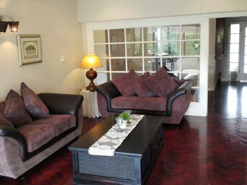 A cozy living room featuring rich herringbone parquet flooring and classic French doors leading to an adjacent space.