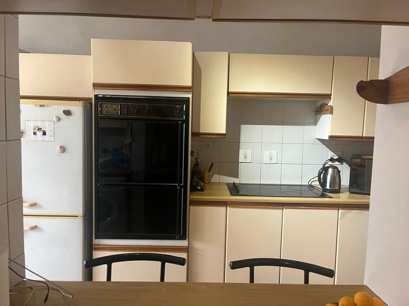 A functional kitchen featuring built-in oven, electric hob, tiled backsplash, and ample cabinetry, offering a classic layout ready for modern updates.