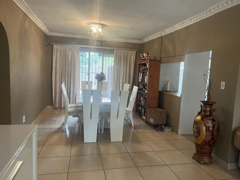 Dining area featuring ceramic floor tiles, decorative ceiling cornices, and a sliding glass door providing access to the exterior.