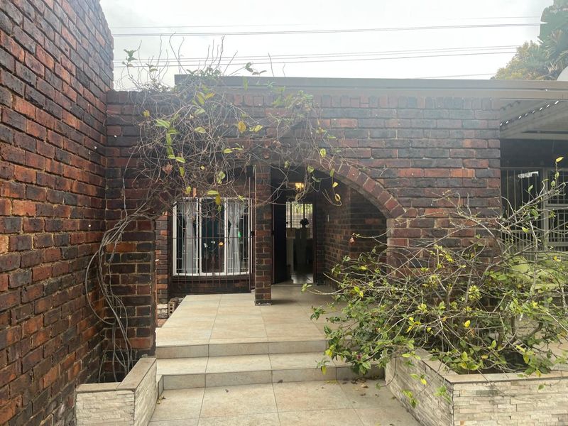 Front entrance of a townhouse featuring a distinctive brick facade with an arched entryway and tiled porch area.