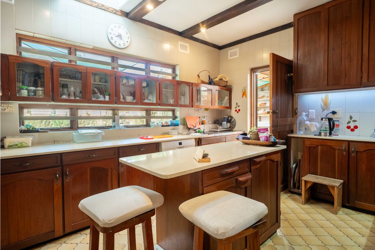 A traditional kitchen featuring wooden cabinetry, stone countertops, a central island, and exposed ceiling beams, offering a warm and functional cooking space.