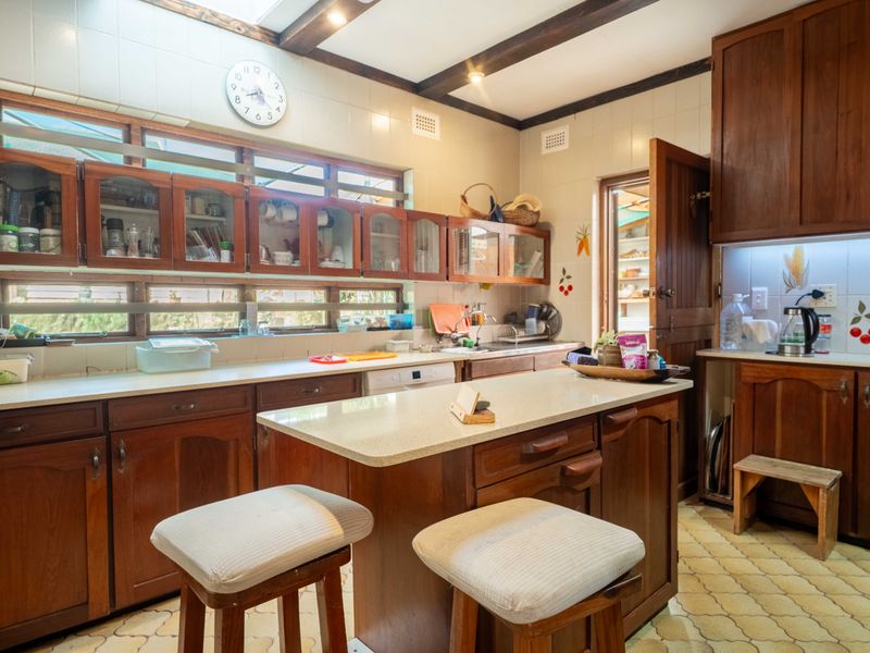 A traditional kitchen featuring wooden cabinetry, stone countertops, a central island, and exposed ceiling beams, offering a warm and functional cooking space.