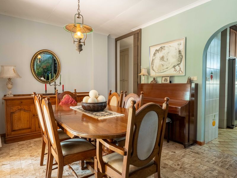 A traditional dining room featuring tiled flooring, coved ceilings, and an arched entryway leading to the kitchen area.