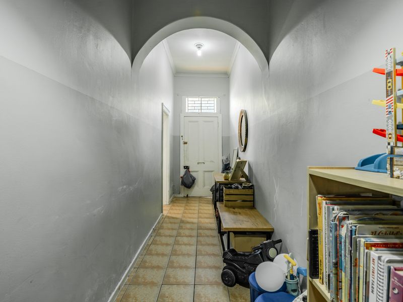 A functional hallway featuring an arched entryway, tiled flooring, and a transom window above the main door.