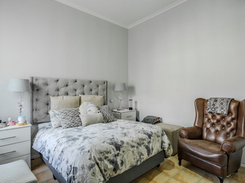 A well-proportioned bedroom featuring neutral wall finishes and durable tiled flooring, offering a comfortable and functional living space.