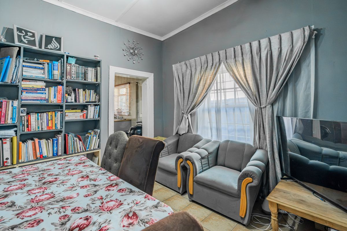 A living room featuring tiled flooring and a built-in shelving unit, with a view through to an adjacent room.