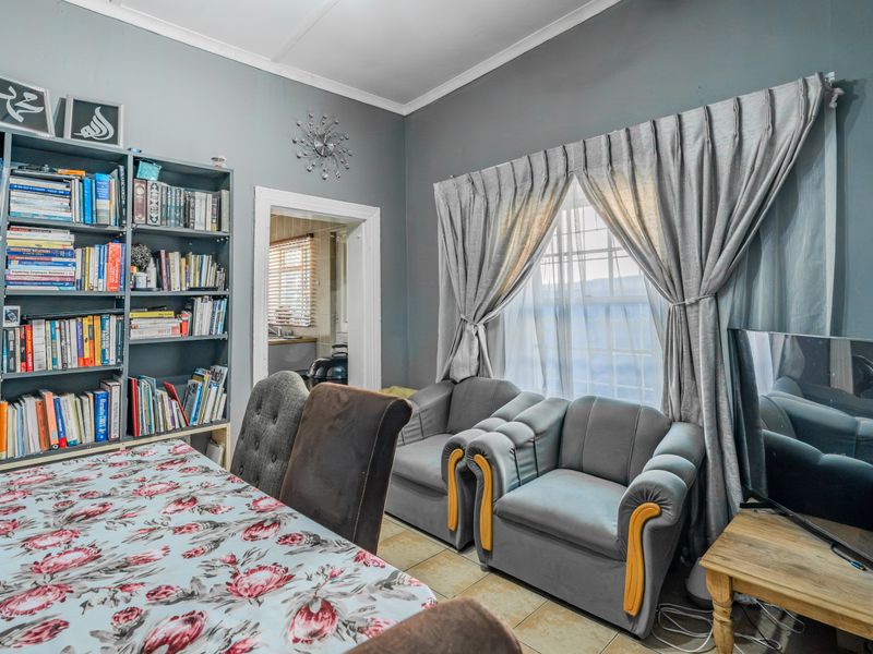 A living room featuring tiled flooring and a built-in shelving unit, with a view through to an adjacent room.