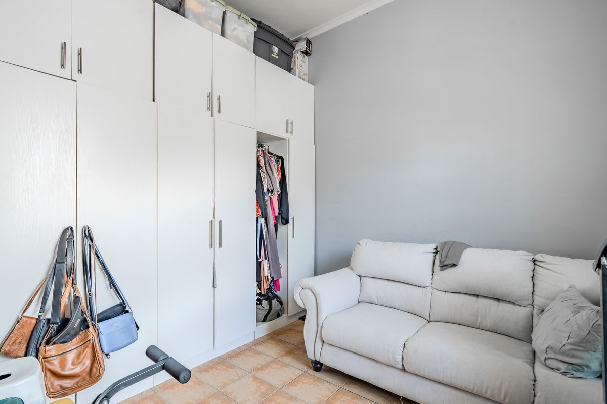 A bedroom featuring floor-to-ceiling built-in cupboards and tiled flooring, offering practical storage space.