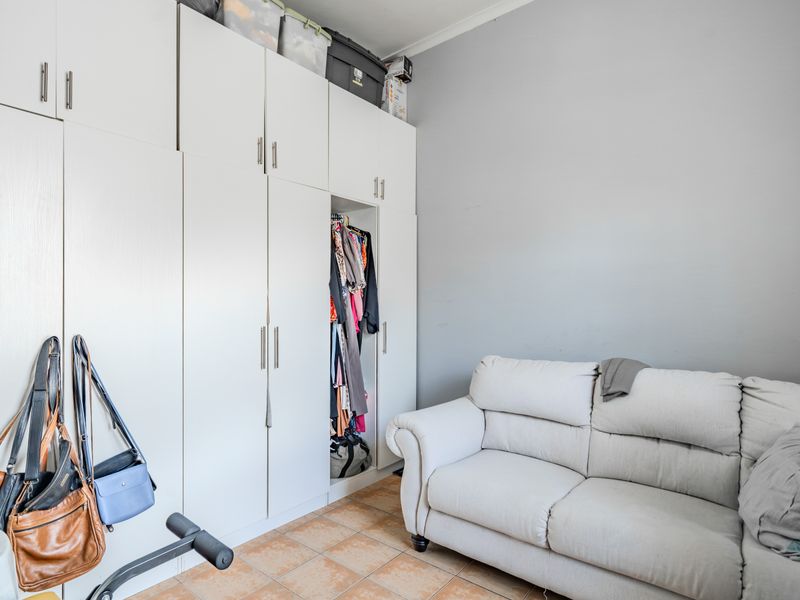 A bedroom featuring floor-to-ceiling built-in cupboards and tiled flooring, offering practical storage space.