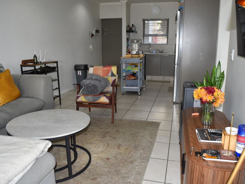 An open-plan living area featuring tiled flooring and a functional kitchen space with built-in cabinetry and sink.