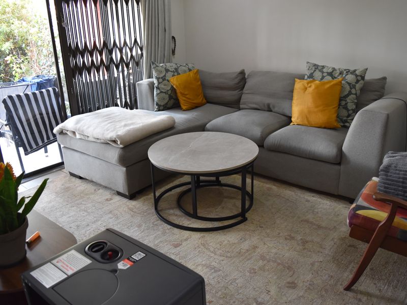 A comfortable living room featuring tiled flooring and a large sliding glass door with a security gate leading to an outdoor area.