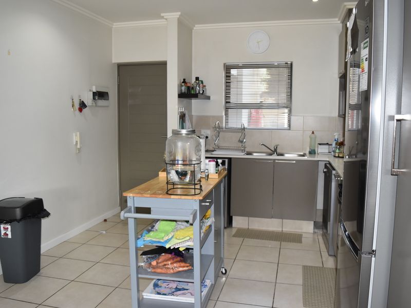 A functional kitchen featuring tiled flooring, built-in cabinetry, a double sink with mixer tap, and a tiled splashback.