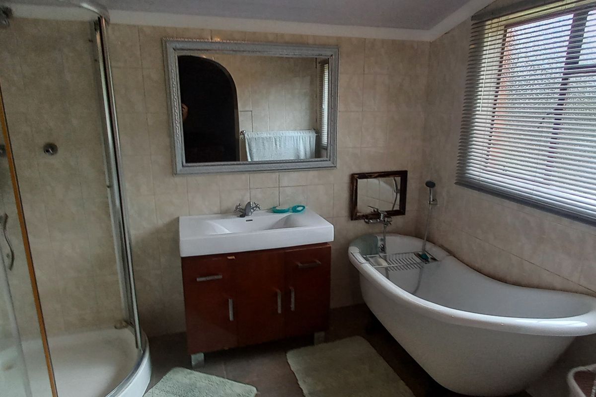 A functional bathroom featuring a corner shower enclosure, a classic freestanding bathtub, and a modern vanity unit with a basin.