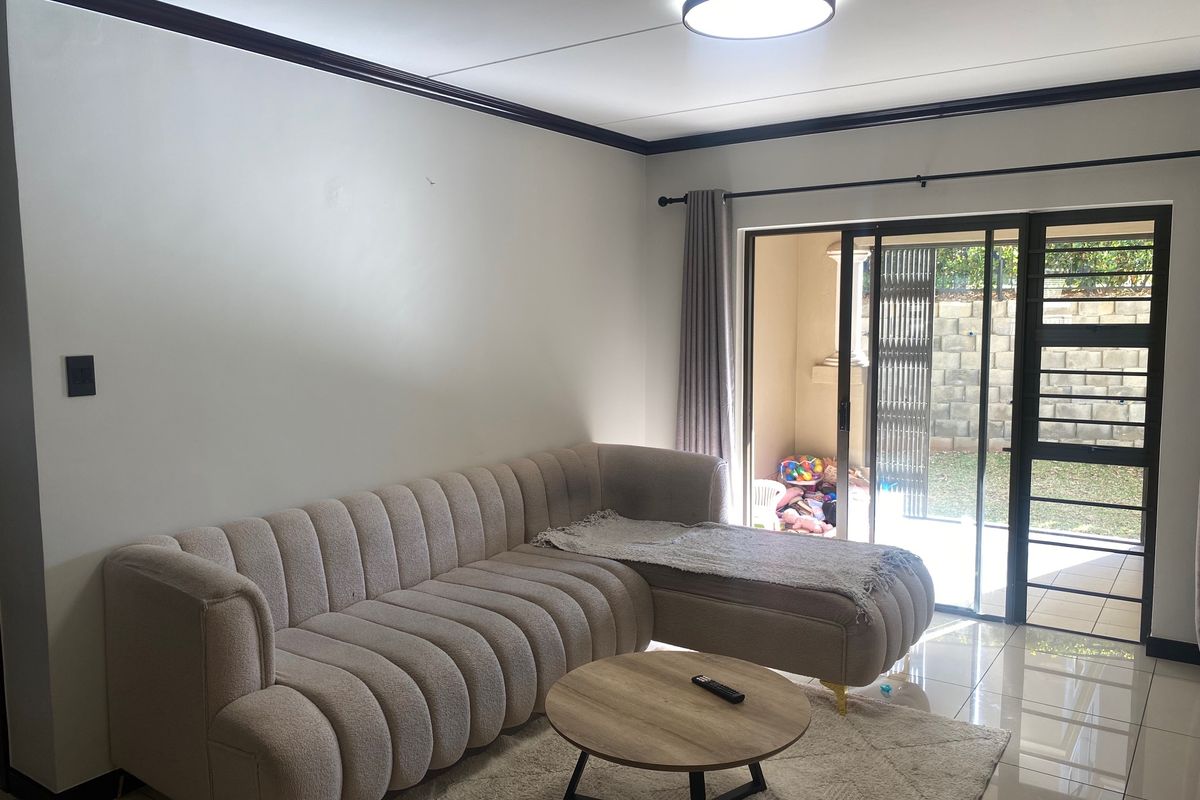 A bright living room featuring tiled flooring and a large sliding glass door that provides direct access to the outdoor patio area.