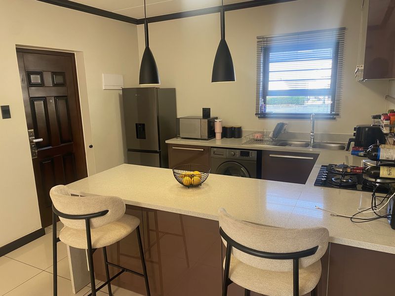 Modern kitchen featuring a central island with stone countertops, built-in cabinetry, gas hob, and integrated sink, complemented by stylish pendant lighting.
