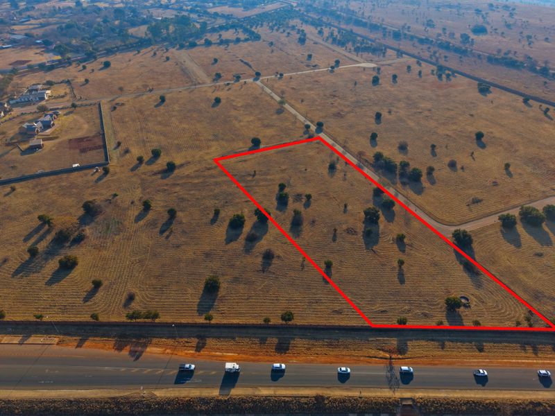 Aerial view of a vacant residential plot with clear boundary markings, situated in a developing estate with road access.