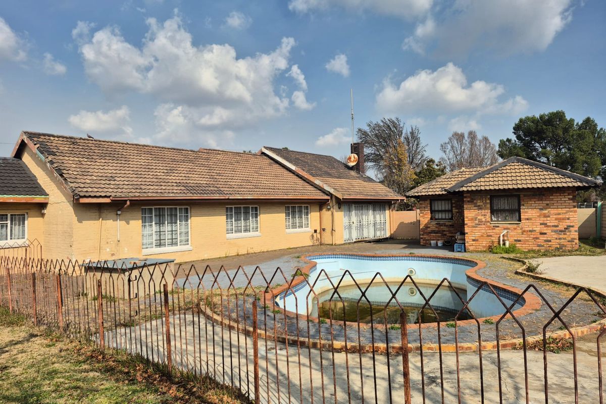 Rear exterior view of the property featuring a swimming pool, brick facade, and detached outbuilding structure.
