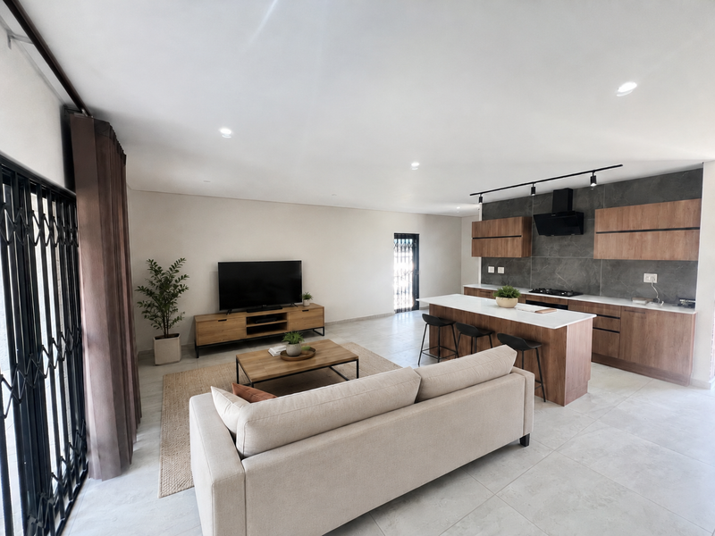 Modern open-plan living area featuring a sleek kitchen with stone countertops, built-in cabinetry, and a central island, seamlessly flowing into the lounge space.