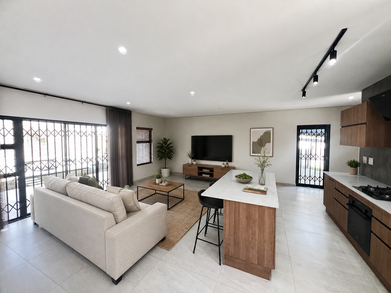 Modern open-plan living area featuring a sleek kitchen with stone island, built-in appliances, tiled floors, and direct access to the exterior via security gates.