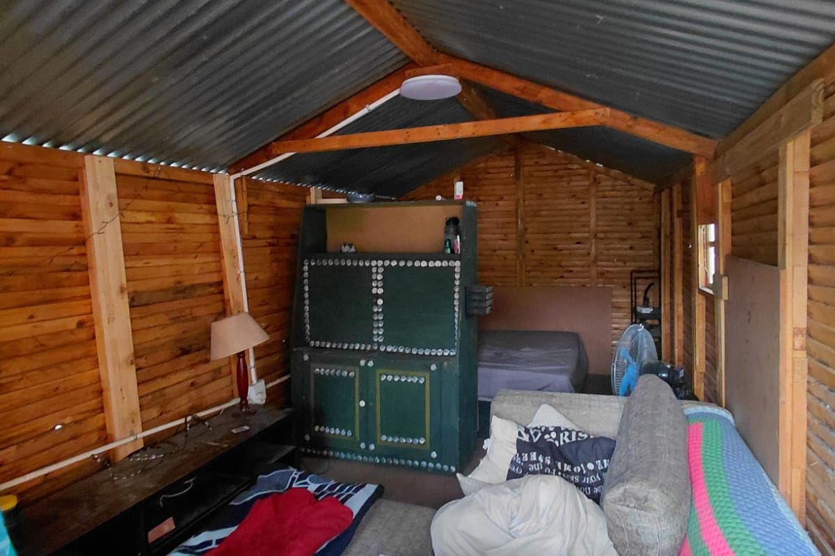 A rustic timber-framed structure with a corrugated metal roof, currently utilized as a multi-purpose living and sleeping space.