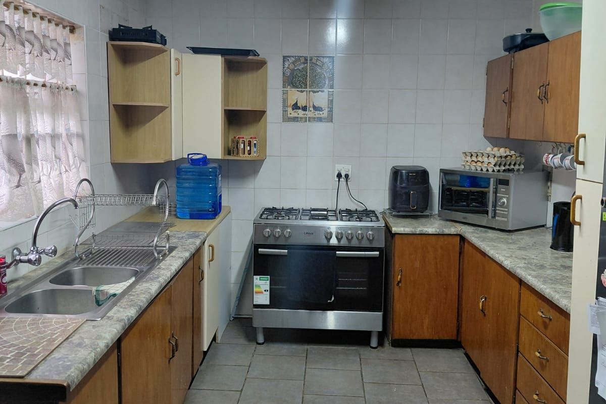 Functional kitchen featuring tiled walls, laminate countertops, double basin sink, and a freestanding gas stove with extractor.