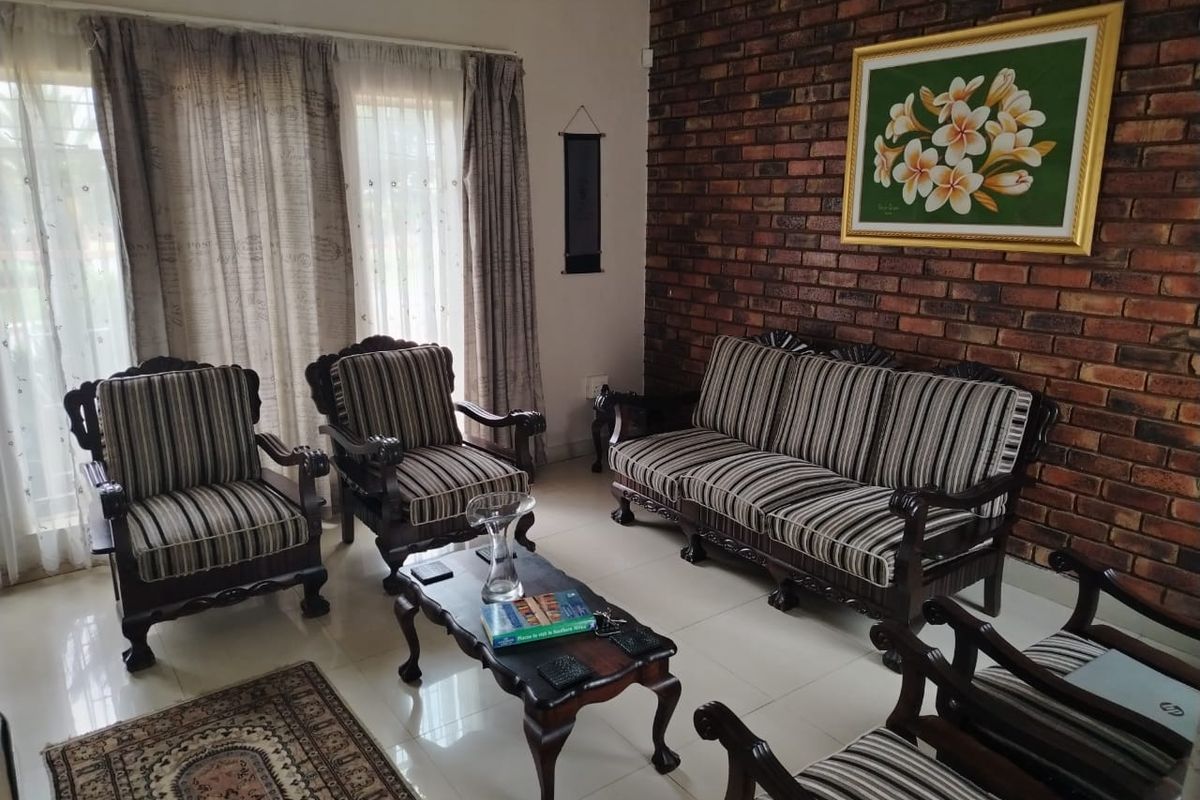 A living room featuring a prominent exposed brick feature wall, large sliding glass doors with curtains, and polished floor tiles.